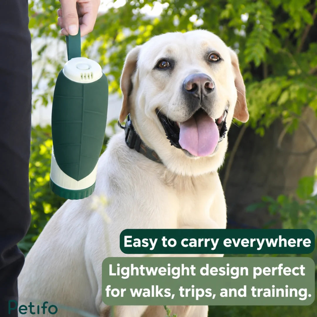 Person holding a green Petifo portable dog water bottle next to a smiling labrador dog during an outdoor walk.