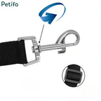 Close-up of a 360-degree rotating metal carabiner and adjustable strap buckle on a black pet seat belt.