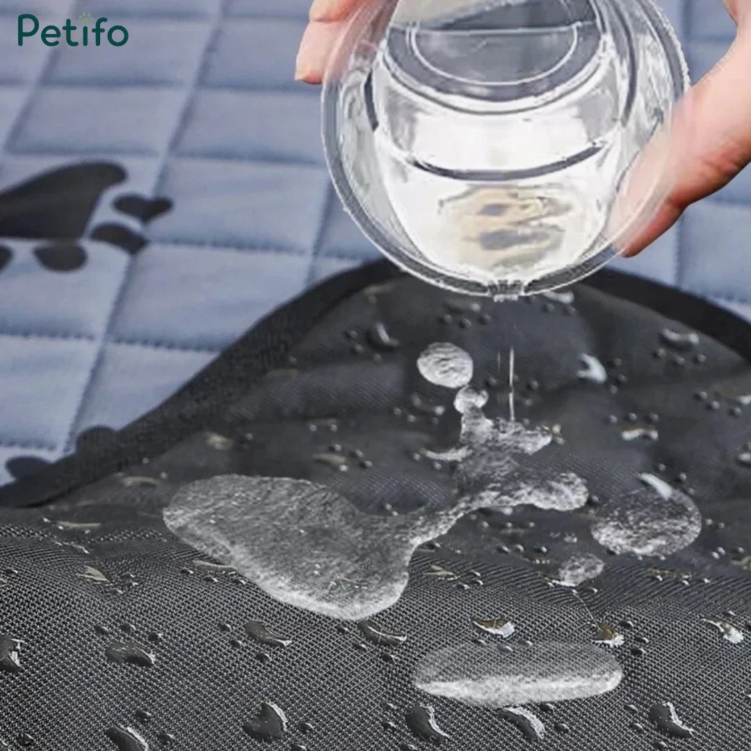 Water being poured onto a black waterproof pet training mat to demonstrate liquid resistance and absorption.