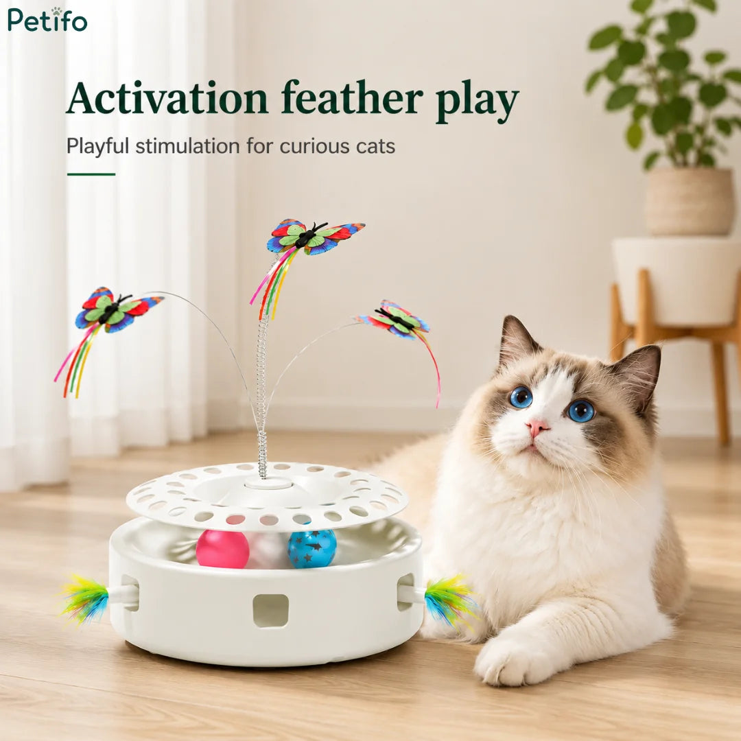 A curious cat resting beside a white automatic cat toy featuring active feather play and colorful butterfly attachments.